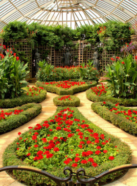 "This image shows the glass-domed Phipps Conservatory & Botanical Gardens, with lush plants and flowers surrounding the exterior. It highlights the conservatory’s Victorian architecture and the vibrant, colorful nature displays that greet visitors at the entrance."