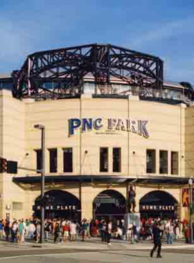 "This image shows PNC Park filled with fans during a Pittsburgh Pirates baseball game, overlooking the iconic skyline and river. The stadium’s riverside view and lively atmosphere are showcased, emphasizing why it’s considered one of the most scenic ballparks."
