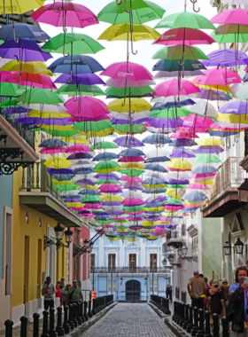 This image shows the vibrant, cobblestone streets of Old San Juan lined with colorful colonial buildings. Bright facades in shades of pink, blue, and yellow create a lively scene, inviting visitors to explore Puerto Rico’s rich history and culture.