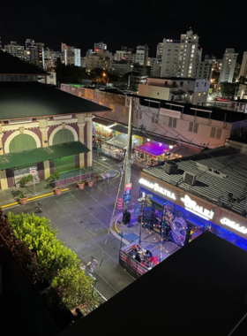 This image shows La Placita de Santurce’s bustling market, with vibrant stalls displaying fresh fruits and vegetables. People are seen shopping, and the lively atmosphere captures the essence of Puerto Rican culture during the day.