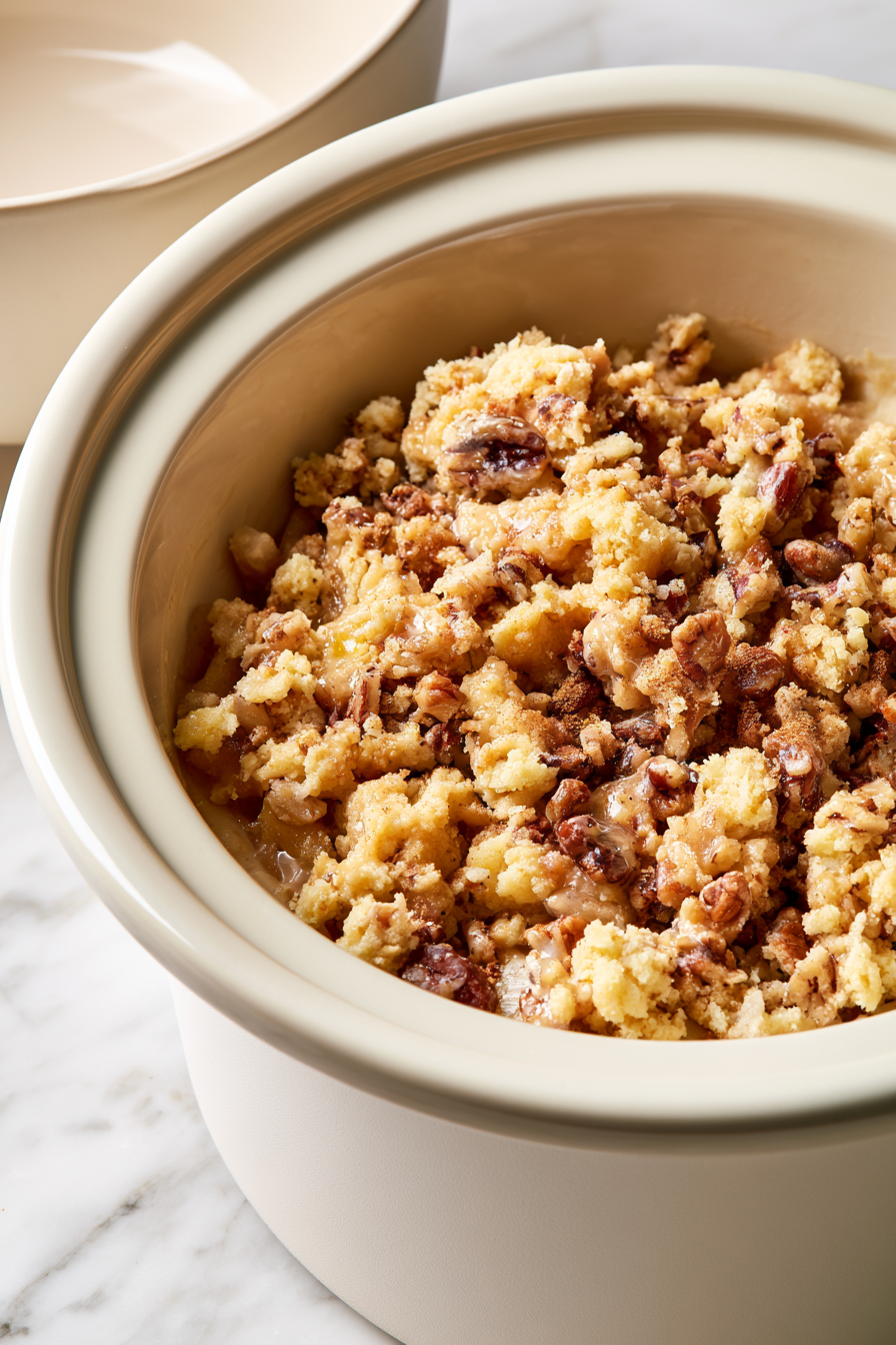 Sprinkle the crumbly mixture evenly over the apple pie filling in the crockpot