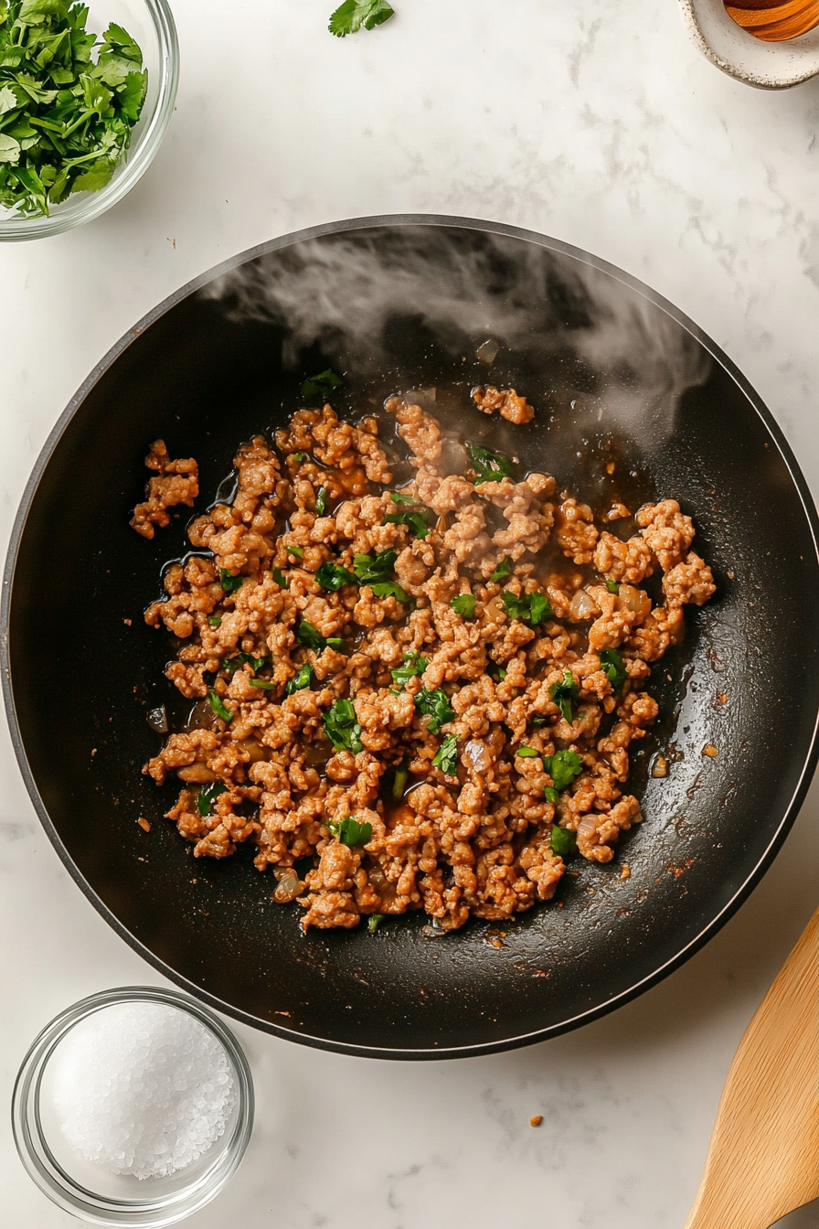 In a skillet, cook ground chicken with garlic, ginger, salt, and pepper until done.