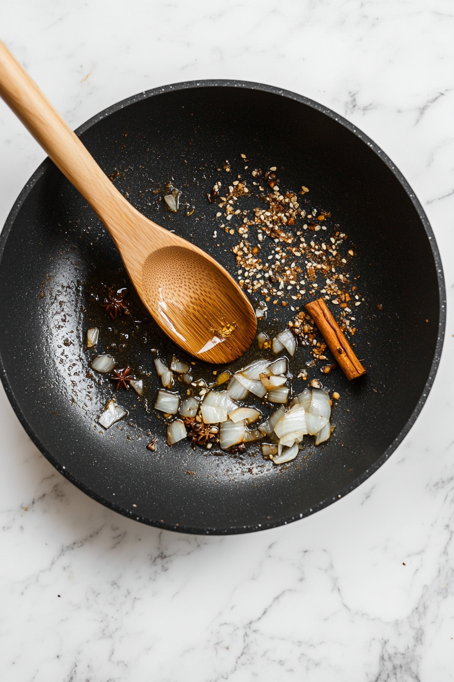 Heat oil or ghee in a heavy pan, add whole spices, then sauté onions till golden brown.