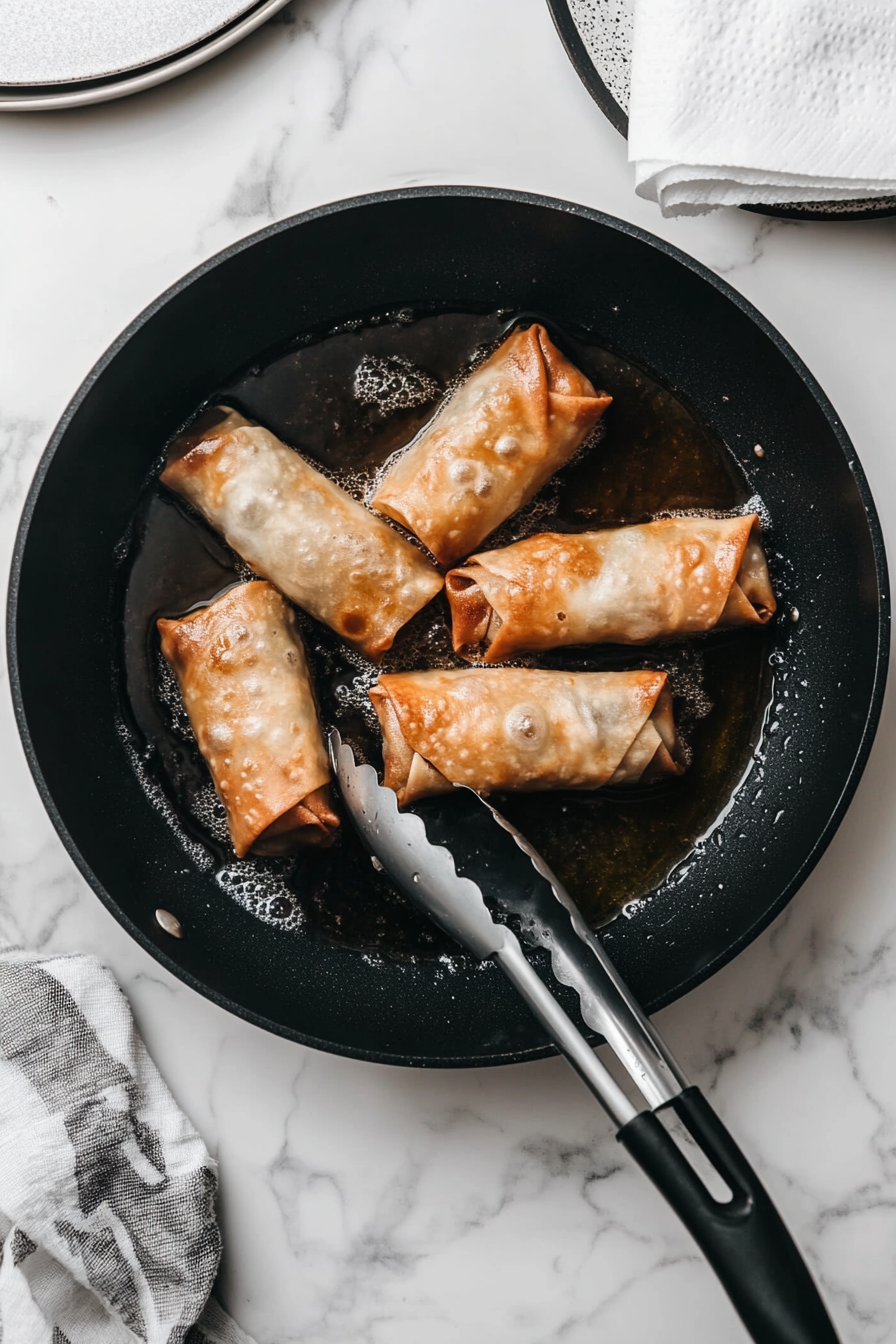 Fry egg rolls in batches until golden brown, about 2–3 minutes per side.