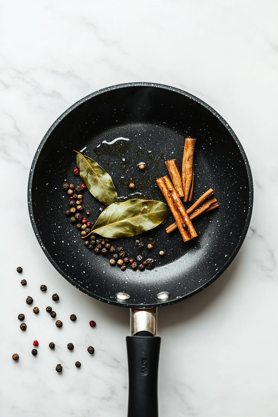 Heat oil in a pan and add bay leaf, cinnamon stick, cloves, and peppercorns.