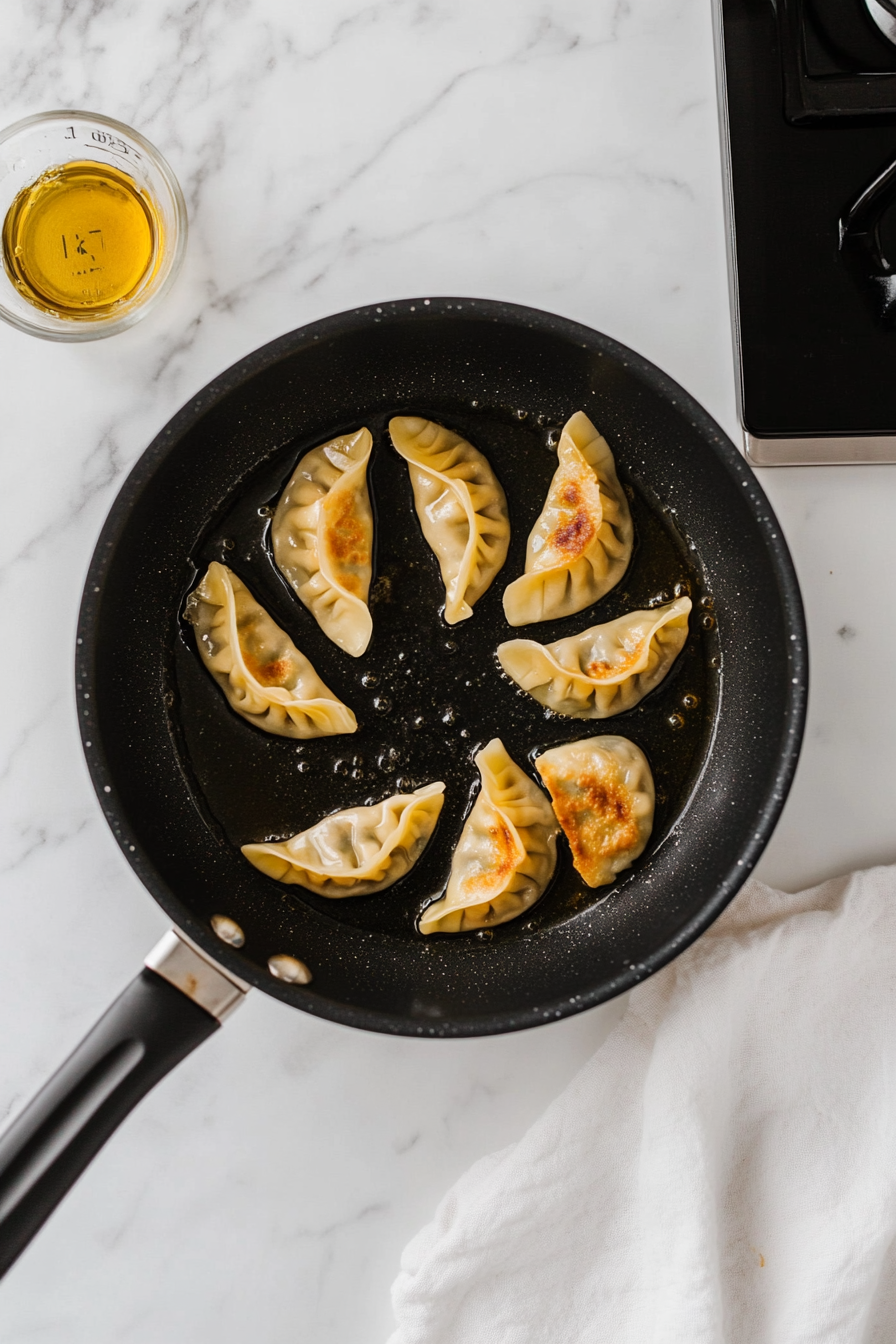 Heat oil in a frying pan over medium heat. Place gyoza flat-side down and cook until bottoms are golden brown (about 2-3 minutes).