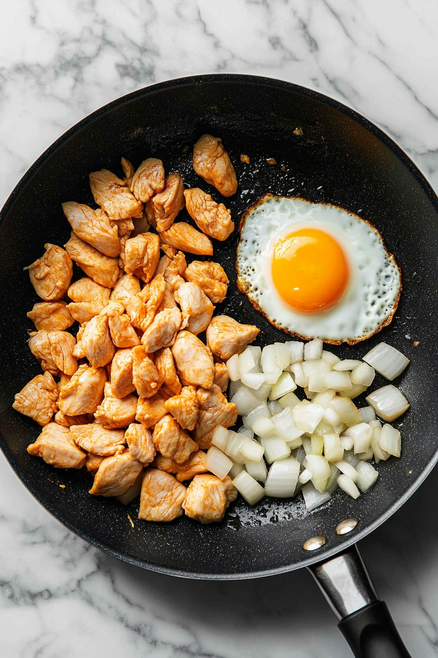 Push chicken to the side, crack an egg into the pan, and scramble.