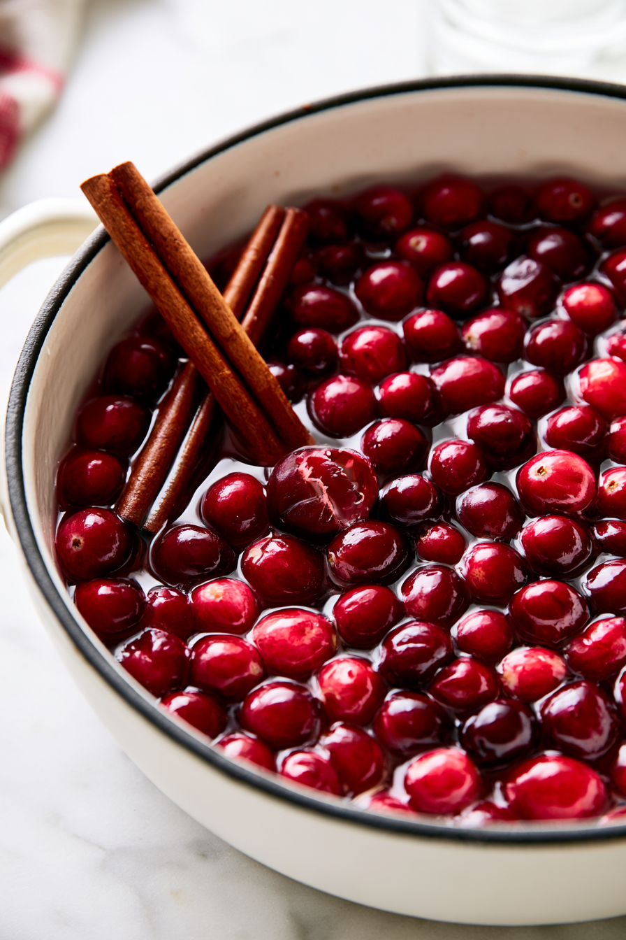 Add the fresh cranberries to the simmering water, watching as they distribute evenly and start to slightly burst