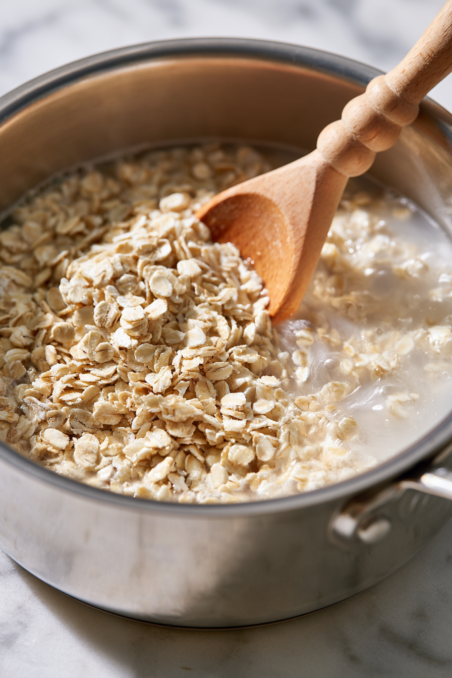 Add the rolled oats to the simmering liquid, stirring with a wooden spoon