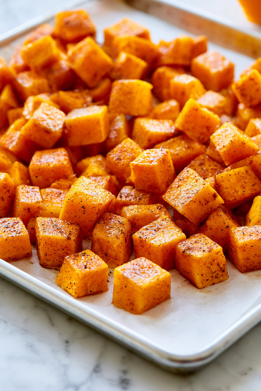 While the quinoa cooks, toss the diced pumpkin with a tablespoon of olive oil, cinnamon, salt, and pepper, then spread evenly on a baking sheet