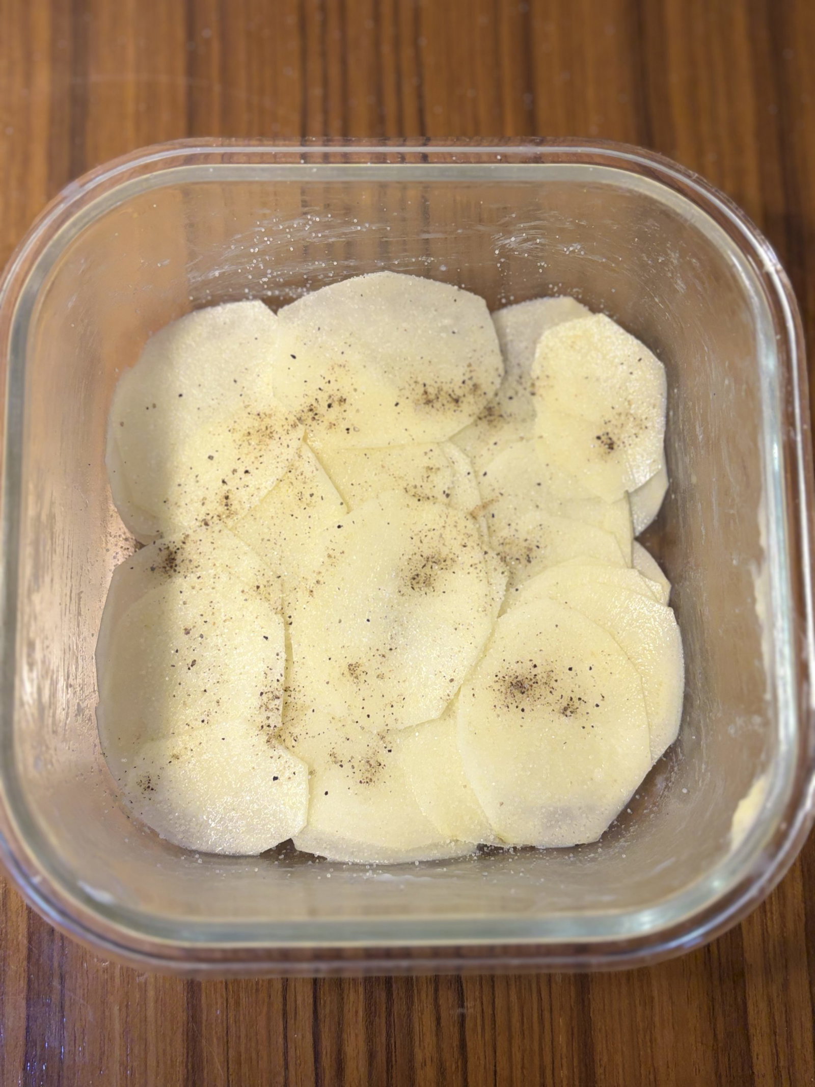 Arrange half of the sliced potatoes in the dish. Season with salt and pepper and scatter half of the sliced onions evenly over the top.