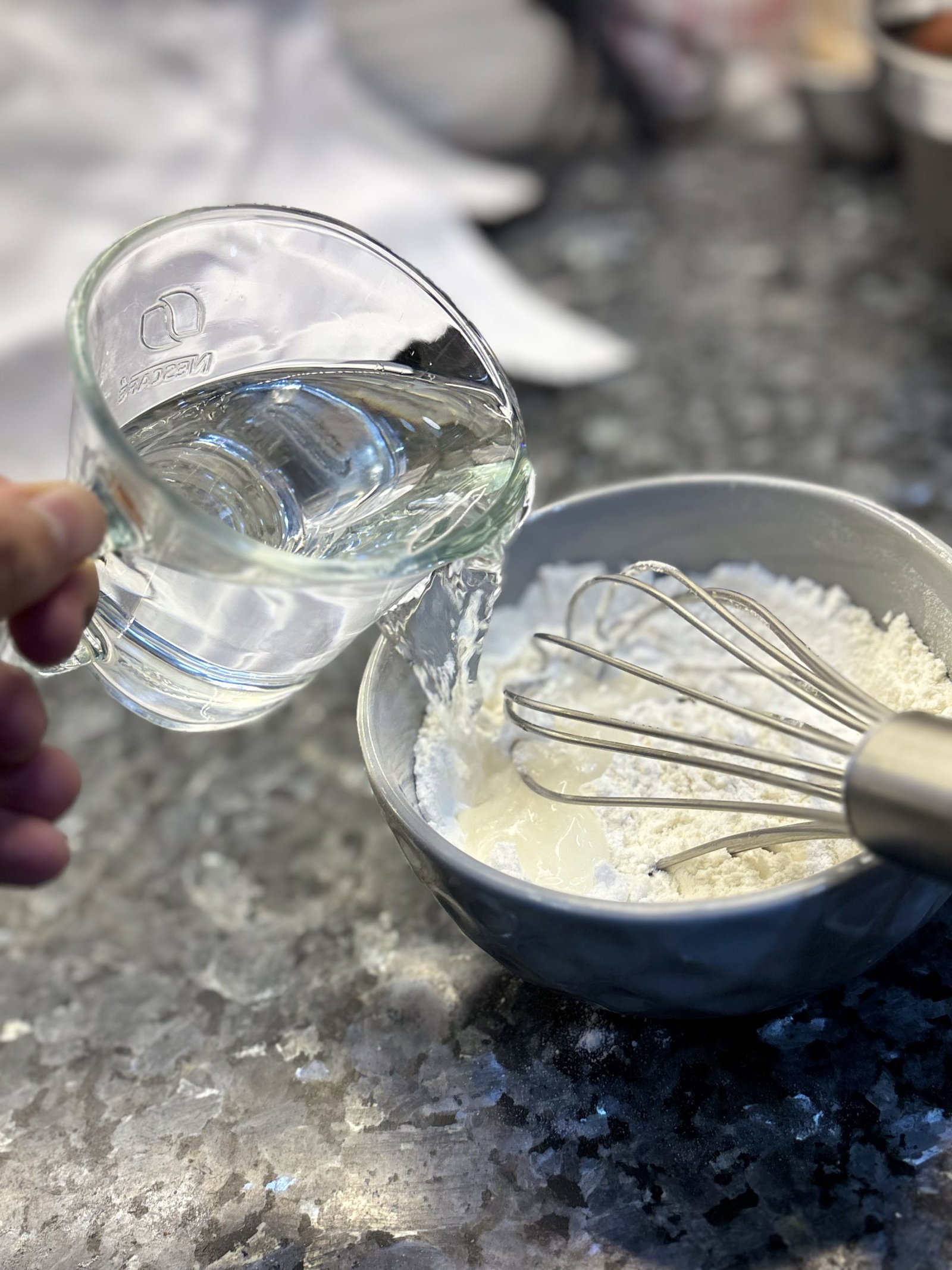 Gradually add water while stirring, whisking until a smooth, lump-free batter forms