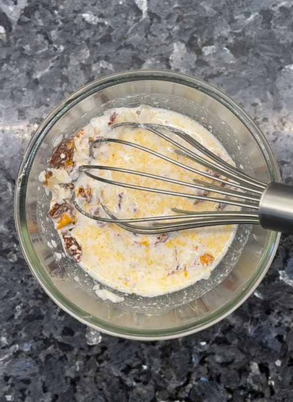 In a bowl, whisk together chicken broth, heavy cream, minced garlic, sun-dried tomatoes, and Parmesan cheese