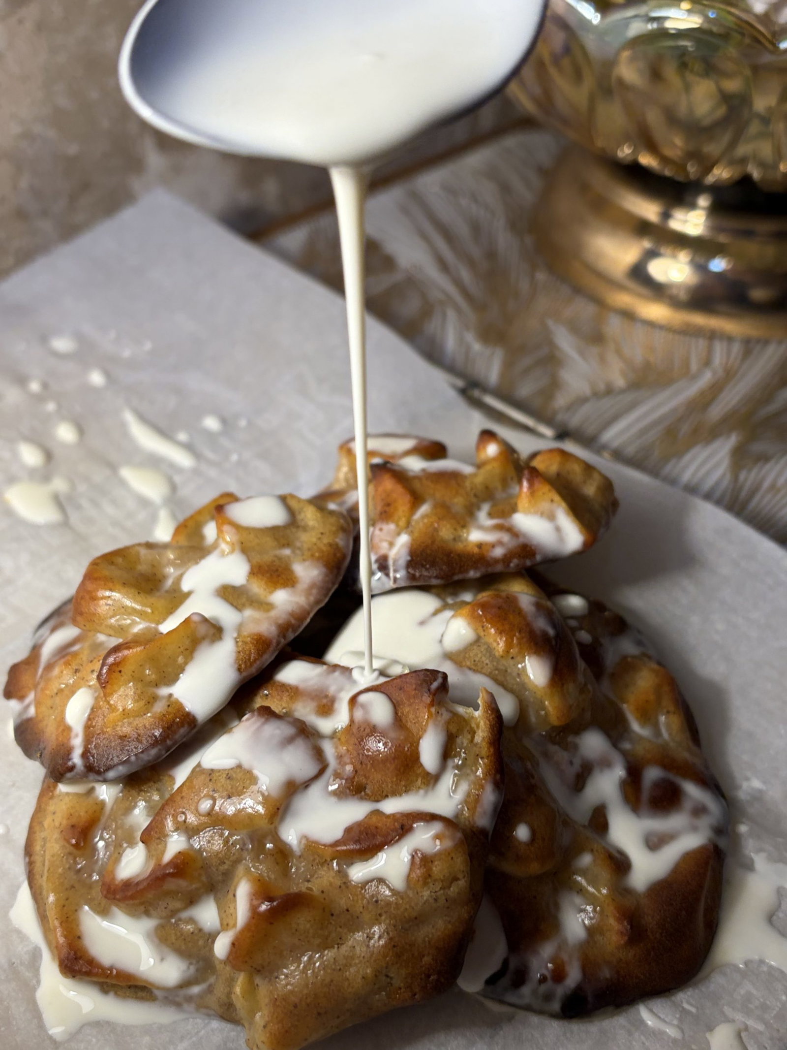 Whisk powdered sugar, milk, and vanilla until smooth. Drizzle glaze over the warm fritters and allow it to set slightly before serving.