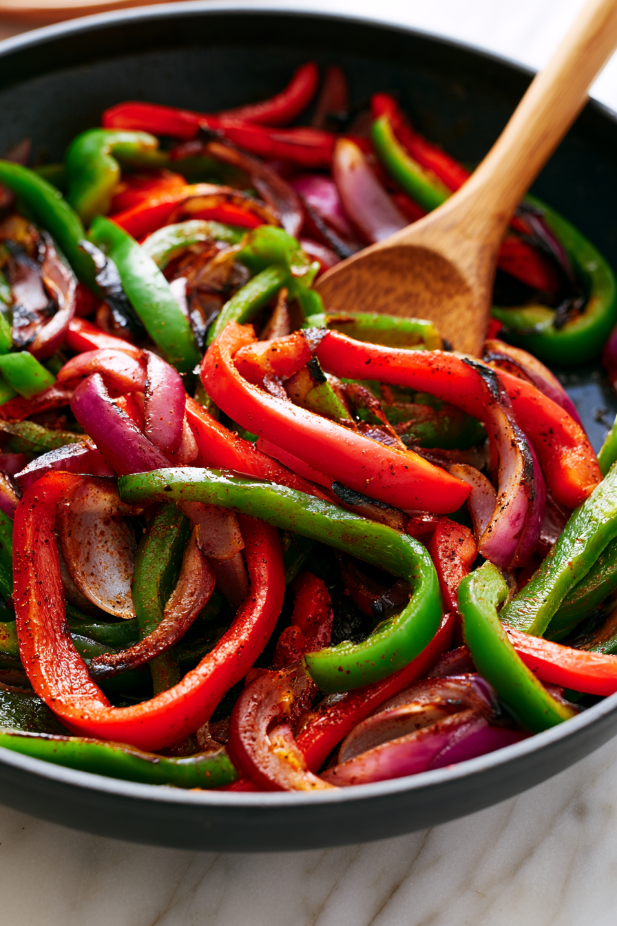 Heat another tablespoon of olive oil in a large skillet over medium-high heat. Add the sliced peppers and onion, then season with oregano, chili powder, salt, and pepper