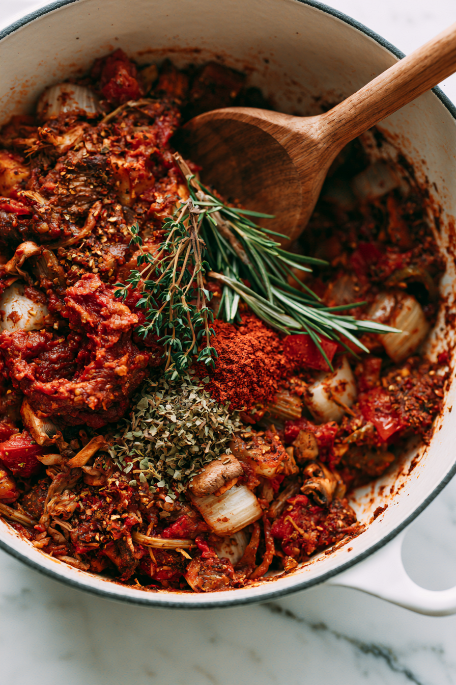 Mix in the tomato paste, thyme, rosemary, oregano, and smoked paprika. Cook for 1 minute, stirring constantly, to toast the spices.