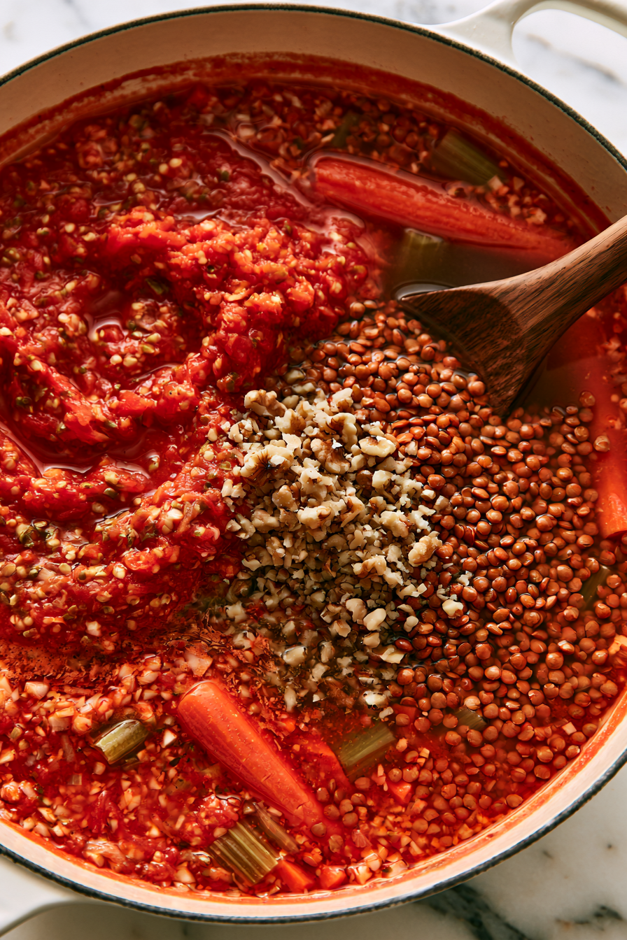 Stir in the crushed tomatoes, vegetable broth, rinsed lentils, and chopped walnuts. Bring the mixture to a gentle boil