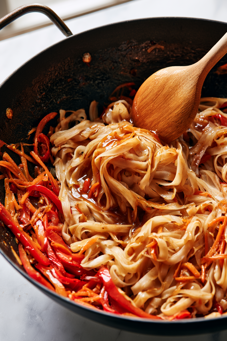 Add the softened rice noodles and pour the prepared Pad Thai sauce over them